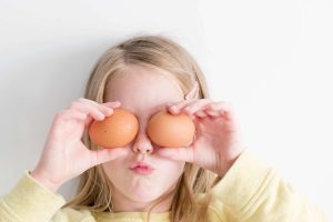 girl holding two boiled eggs over eyes